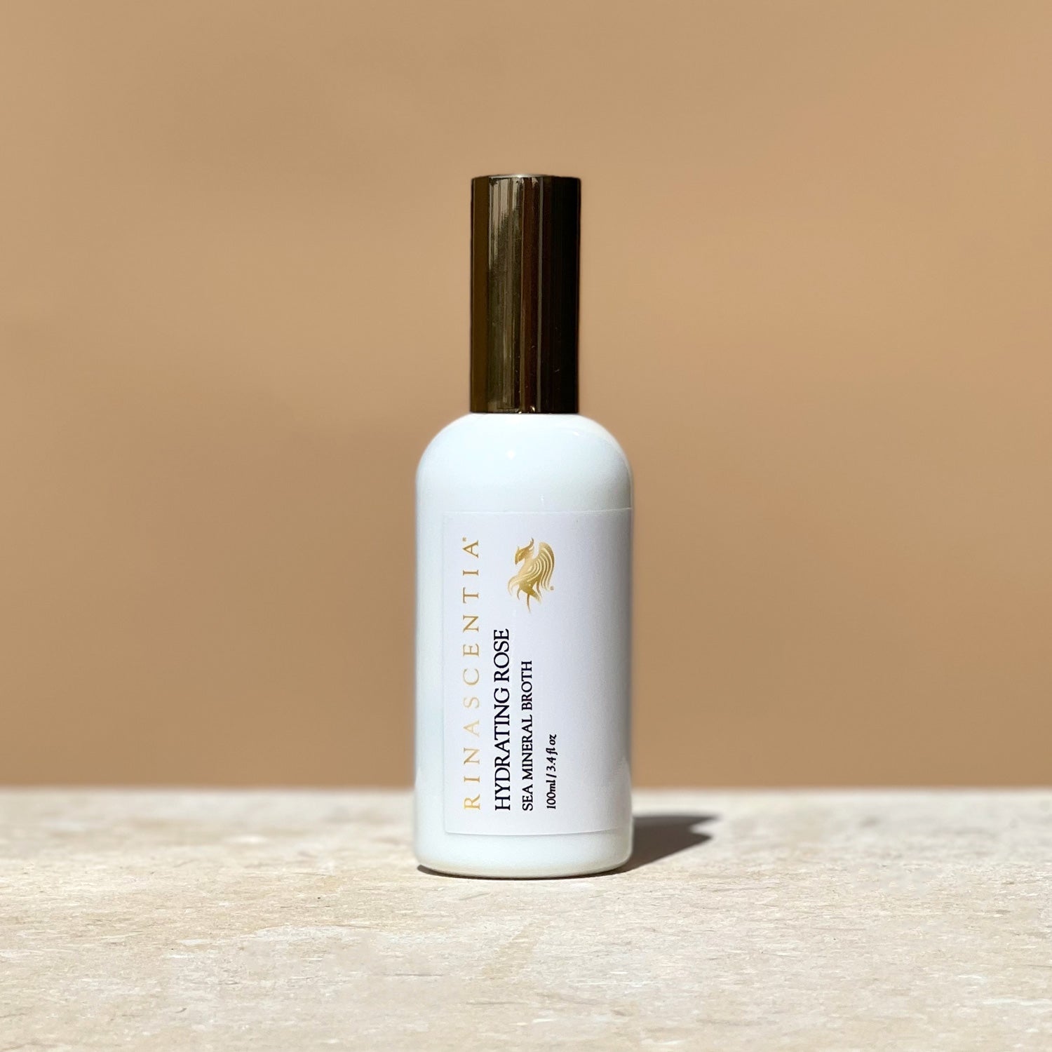 Hydrating Rose sea mineral broth in a bottle with gold lid on limestone base